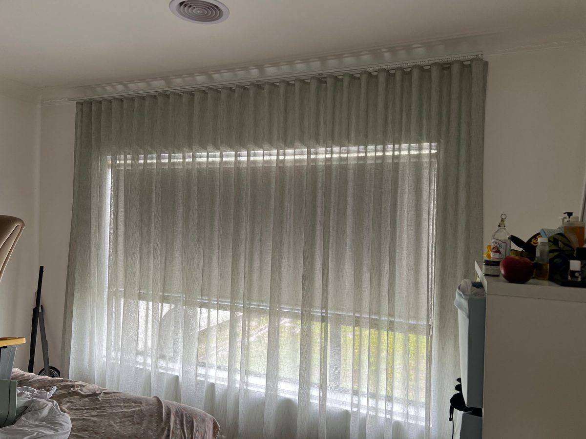 Soft green wave fold sheers across a bedroom window