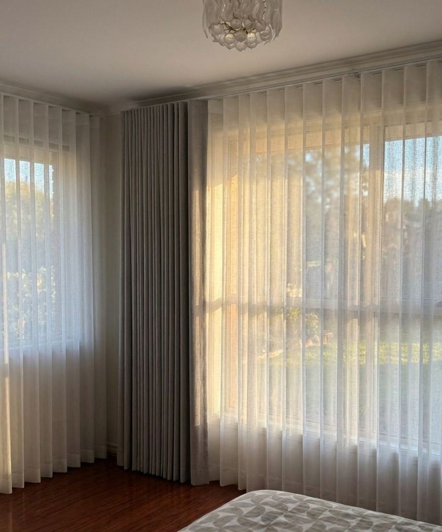 Sheer curtains with a grey blockout panel in a corner bedroom