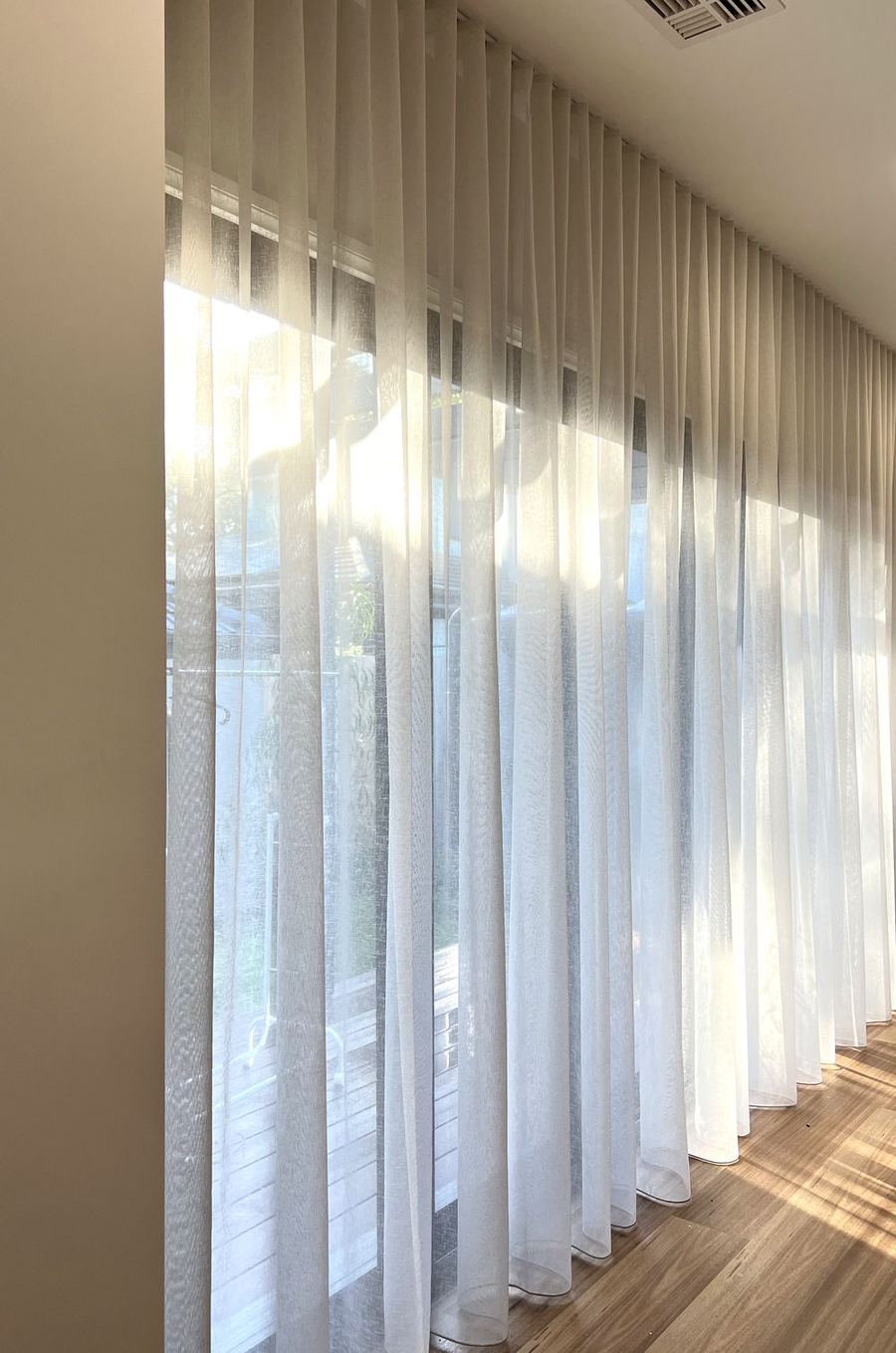 White wave fold sheers along a wall of windows